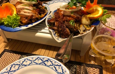 Chinesisches Gericht Knusprig gebratenes Entengericht auf Porzellanteller mit frischen Orangenscheiben und Gemüsebeilage.