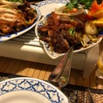 Chinesisches Gericht Knusprig gebratenes Entengericht auf Porzellanteller mit frischen Orangenscheiben und Gemüsebeilage.