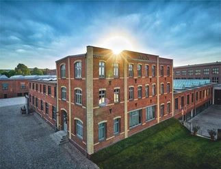 Brick building of the Audi Museum in the evening sun, meadow in the foreground.