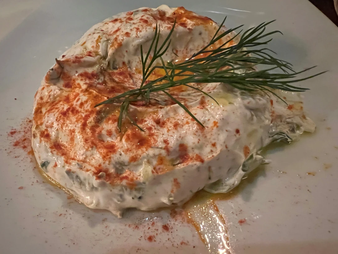 Griechischer Joghurt-Dip auf einem weißen Teller, garniert mit Dill und leicht bestreutem Paprika.Greek yogurt dip on a white plate, garnished with dill and lightly sprinkled paprika.Græsk yoghurtdip på en hvid tallerken, pyntet med dild og let drysset paprika.Griekse yoghurtdip op een wit bord, gegarneerd met dille en licht bestrooid met paprikapoeder.