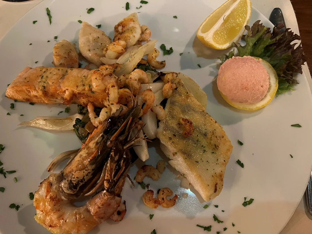 Fischteller Ein Teller mit verschiedenen Fischsorten, Garnelen und einer Zitronenspalte auf dekorativem Salat.A plate with different types of fish, prawns and a lemon wedge on a decorative salad.En tallerken med forskellige typer fisk, rejer og en citronbåd på en dekorativ salat.Een bord met verschillende soorten vis, garnalen en een partje citroen op een decoratieve salade.