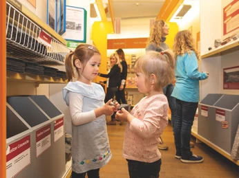 Baumarkt Zwei Kinder inspizieren Steine in einem Baumarkt, während Erwachsene im Hintergrund stöbern.Two children inspect stones in a DIY store while adults browse in the background.Dvě děti si prohlížejí kameny v obchodě pro kutily, zatímco v pozadí si je prohlížejí dospělí.Dwoje dzieci ogląda kamienie w sklepie dla majsterkowiczów, podczas gdy dorośli przeglądają je w tle.Twee kinderen inspecteren stenen in een bouwmarkt terwijl volwassenen op de achtergrond snuffelen.Due bambini ispezionano le pietre in un negozio di bricolage mentre gli adulti curiosano sullo sfondo.