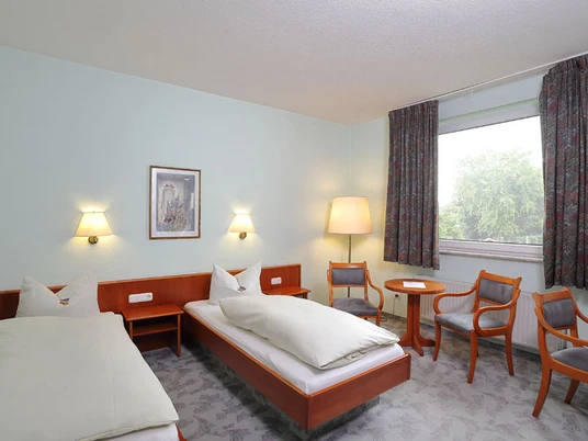 Hotel und Restaurant im Loh Zwei Einzelbetten mit weißer Bettwäsche in einem hellen Zimmer, großes Fenster mit Blick auf Bäume.