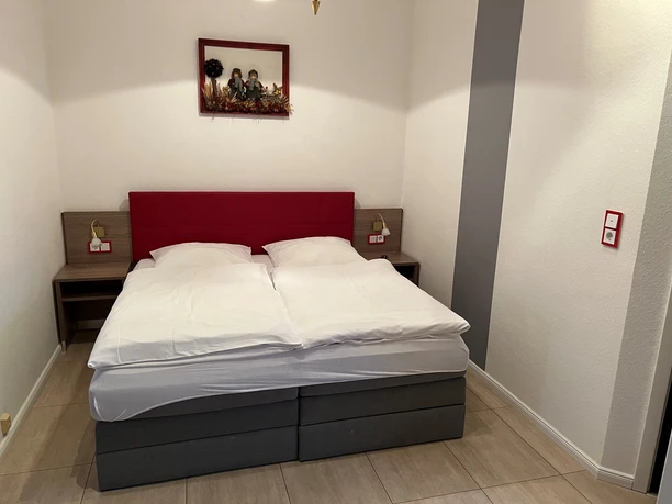 A double bed in a simple, modern room with murals and bedside lamps on wooden tables.