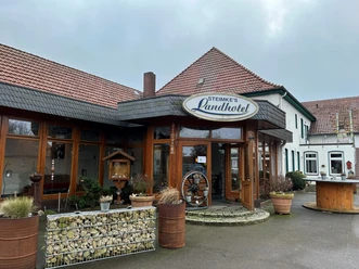 Steimkes Landhotel Eingang Eingang von Steimkes Landhotel mit runden Fenstern, Schindeldach und dezent begrünten Pflanzkübeln.