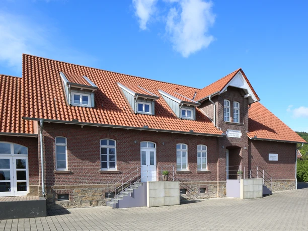 Lübber Volksschule Ehemalige Lübber Volksschule mit markantem roten Ziegeldach, historischen Backsteinwänden und drei Dachgauben.