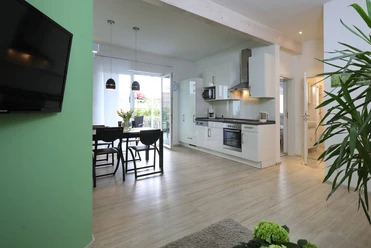 Ferienwohnung_Birke.jpg Moderne Ferienwohnung mit offener Küche, Essbereich und hellem Wohnzimmer, Parkettboden und Balkon.