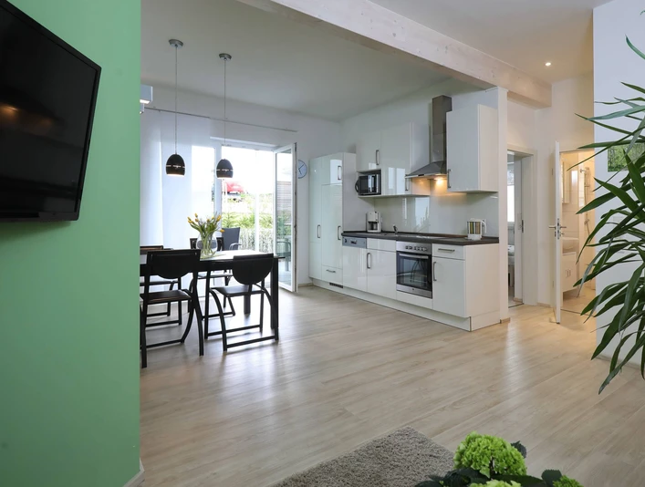 Ferienwohnung_Birke.jpg Moderne Ferienwohnung mit offener Küche, Essbereich und hellem Wohnzimmer, Parkettboden und Balkon.