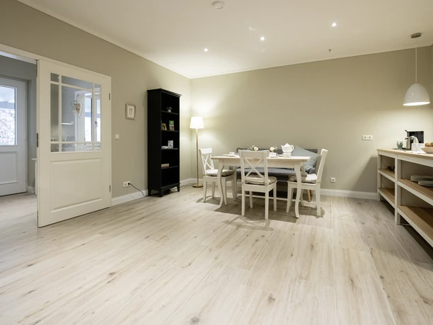 Frühstücksraum mit Holzfußboden Heller Frühstücksraum mit Holzfußboden, gedecktem Esstisch, weißen Stühlen und Anrichte.