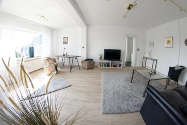 Wohnzimmer Erdgeschoß Geräumiges Wohnzimmer mit hellem Holzfußboden, modernen Möbeln und großen Fenstern für viel Licht.