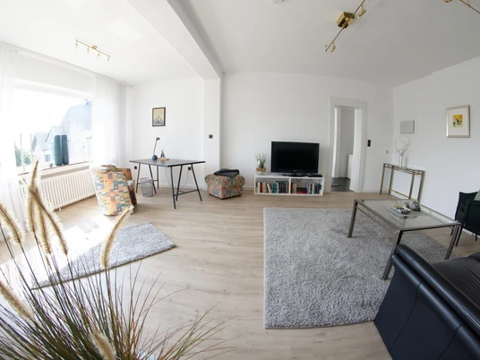 Wohnzimmer Erdgeschoß Geräumiges Wohnzimmer mit hellem Holzfußboden, modernen Möbeln und großen Fenstern für viel Licht.