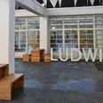 Ludwig Forum Innenhof des Ludwig Forums mit moderner Architektur mit hohen, weißen Säulen und großen Fenstern. Große Buchstaben, die das Wort "LUDWIG" formen, stehen auf dem Boden.