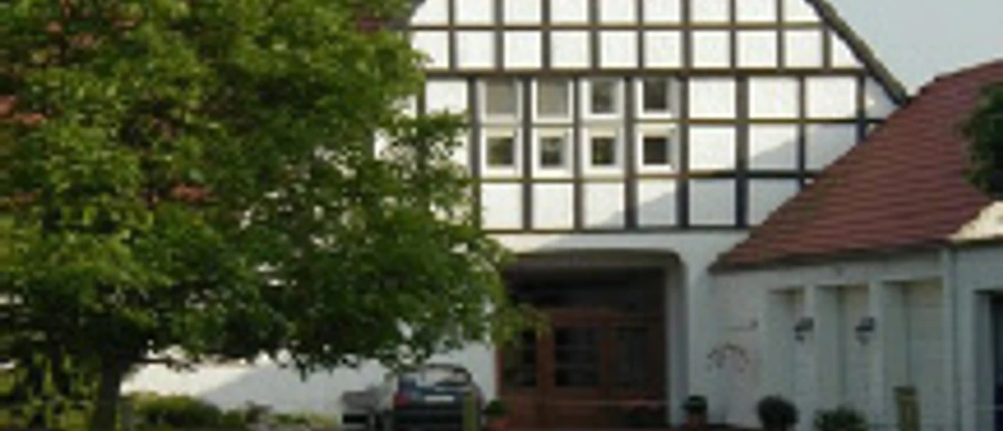 haus-hansen.jpg Fachwerkhaus mit spitzem Giebel, umgeben von grüner Wiese, auf der zwei Pferde grasen.