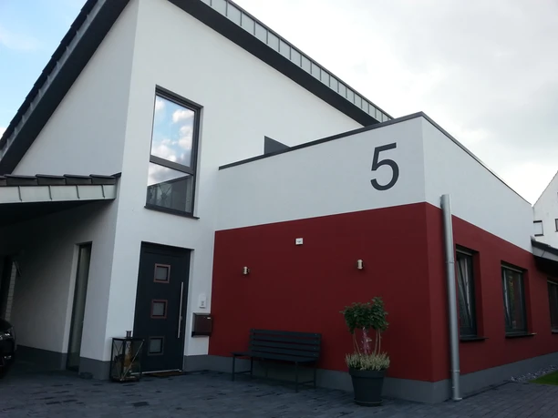 Gaesteappartement-Luebbecke-.jpg Modernes Gästeappartement in Lübbecke mit ansprechender Fassade in Weiß und Rot sowie großen Fenstern.