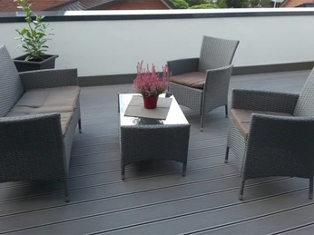 Gaesteappartement-Luebbecke-3.jpg Rattanmöbel-Set auf einer Terrasse mit grauem Boden, bestehend aus zwei Sesseln, einem Sofa und Tisch.