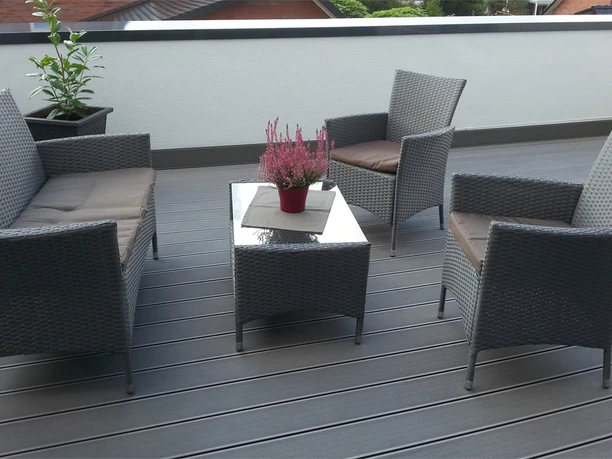 Gaesteappartement-Luebbecke-3.jpg Rattanmöbel-Set auf einer Terrasse mit grauem Boden, bestehend aus zwei Sesseln, einem Sofa und Tisch.
