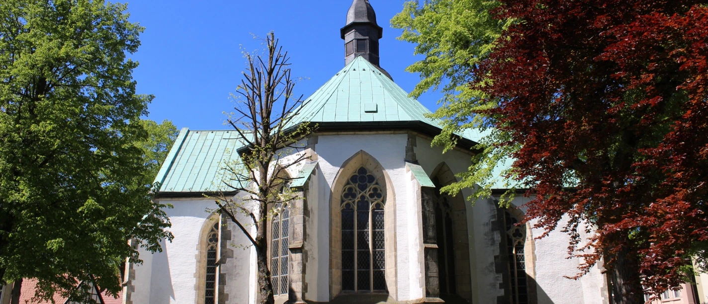 Ev. Stadtkirche Horn Evangelische Stadtkirche Horn mit gotischen Fenstern, umgeben von grünen und roten Laubbäumen.