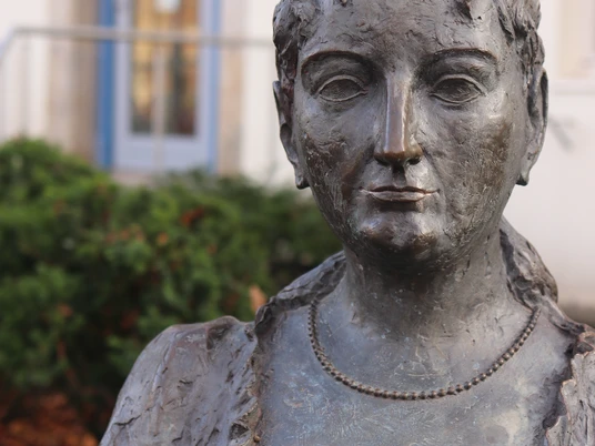 Pauline Bronzestatue einer Frau mit detaillierten Gesichtszügen und lockigem Haar, nah aufgenommen.