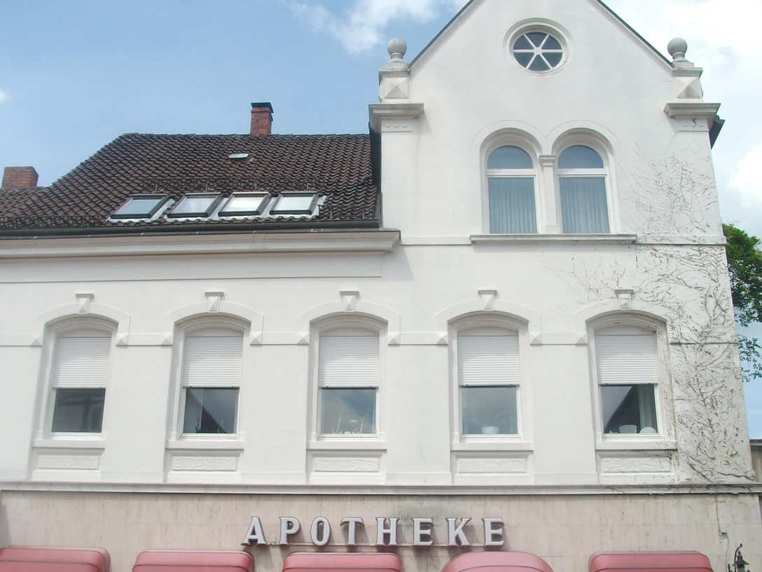 Haus Mittelstraße.jpg Ein weißes, zweistöckiges Gebäude mit rotem Dach und mehreren Fenstern, das als Apotheke dient.