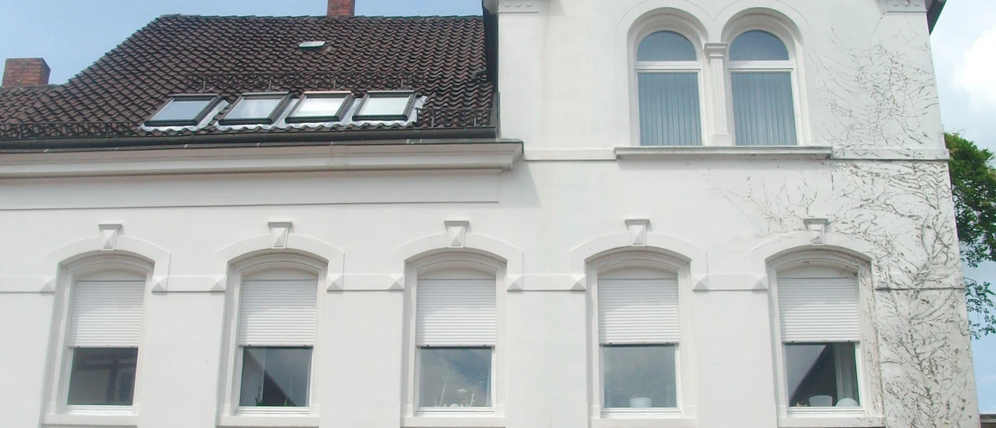 Haus Mittelstraße.jpg Ein weißes, zweistöckiges Gebäude mit rotem Dach und mehreren Fenstern, das als Apotheke dient.