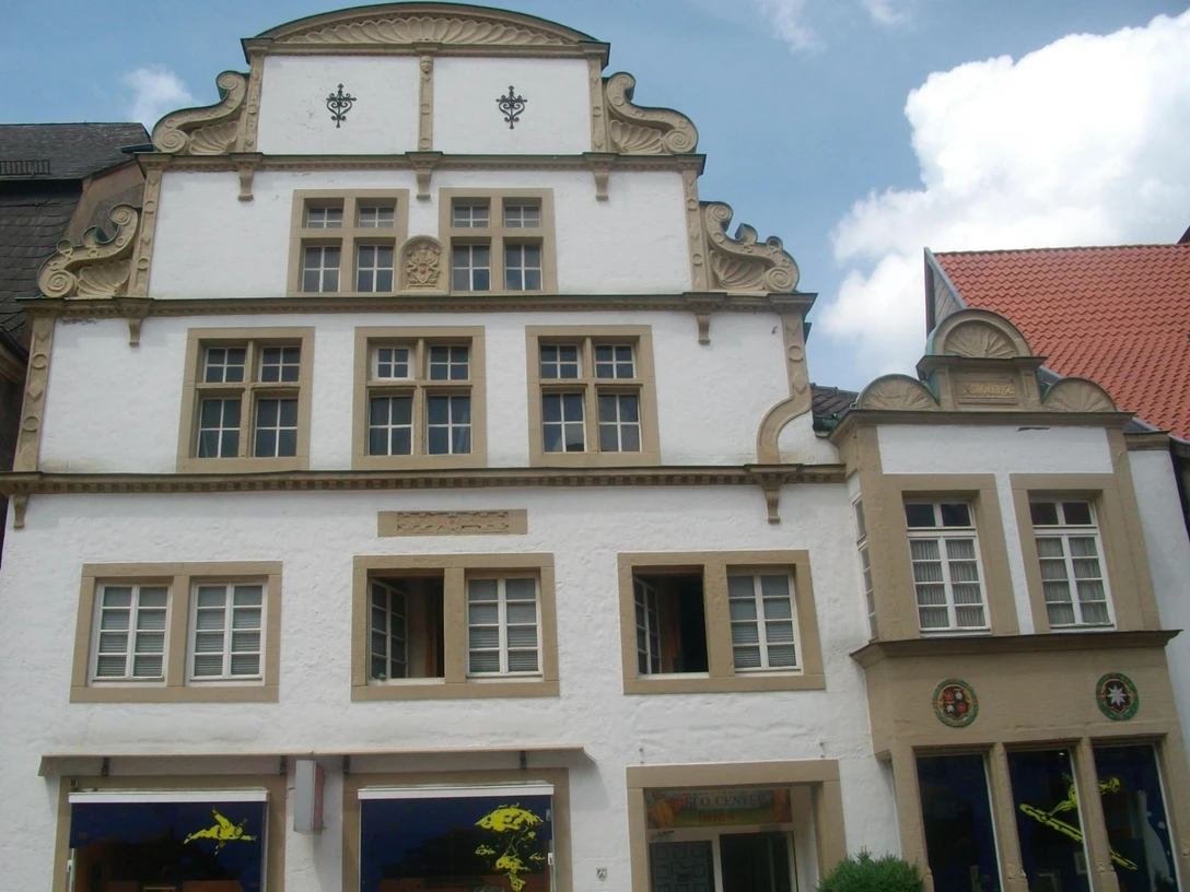 Fachwerkhaus mit dekorativen Giebeln und Sprossenfenstern, umgeben von weiteren historischen Gebäuden.