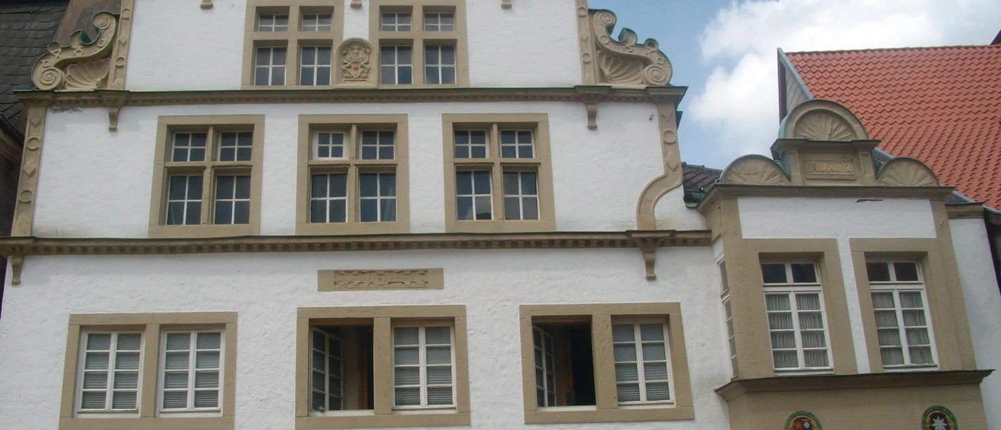 Fachwerkhaus mit dekorativen Giebeln und Sprossenfenstern, umgeben von weiteren historischen Gebäuden.