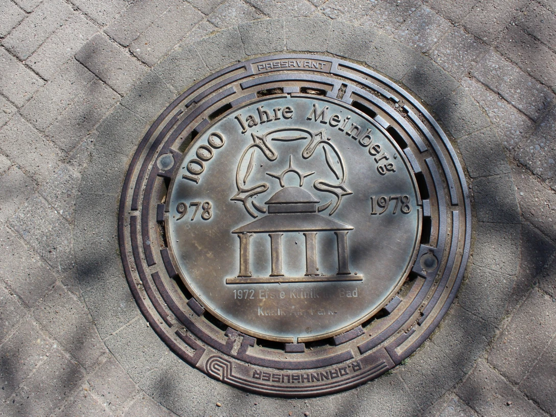 Kanalzierdeckel.png Kanaldeckel in Bad Meinberg, graviert mit "1000 Jahre Meinberg 1978" und einem stilisierten Kurhaus.