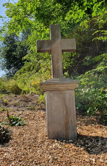 Kreuz am Bickelberg Steinernes Kreuz auf einer Anhöhe umgeben von Bäumen und Grün, mit Lichtspiel der Sonne.