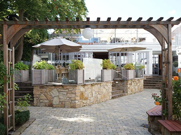 Bürgerpark Schäppchen Eingang zum Bürgerpark Schäppchen mit gemütlichem Vorplatz, Pflastersteinen und hölzernem Pergola.