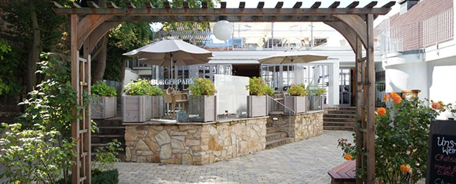 Bürgerpark Schäppchen Eingang zum Bürgerpark Schäppchen mit gemütlichem Vorplatz, Pflastersteinen und hölzernem Pergola.