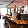 Bürgerpark Schäppchen Restaurant mit modernem Interieur, gedeckten Tischen und natürlichem Licht durch große Fenster.