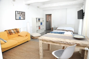 Ferienwohnung Sieveking u. Grünert Helles Wohn- und Schlafzimmer mit gelbem Sofa, Holztisch und Doppelbett in einer modernen Ferienwohnung.
