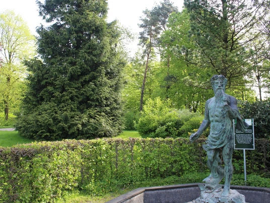 Neptunstatue Neptunstatue im Park, umgeben von üppigem Grün und Bäumen, ein Hinweis auf kulturellen Reichtum.