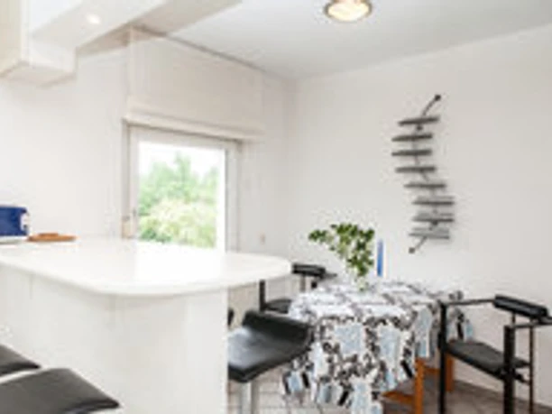 Moderne Küche mit Bartresen, schwarz-weißen Stühlen, Tisch, Fenster und stilvoller Dekoration.