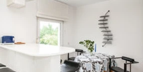 Ferienwohnung Berger 3.jpg Moderne Küche mit Bartresen, schwarz-weißen Stühlen, Tisch, Fenster und stilvoller Dekoration.