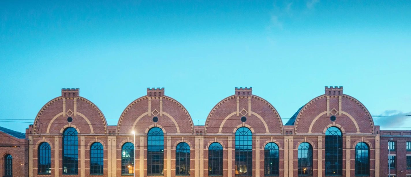 industriemuseum_05692_ernestouhlmann.jpg Backsteinfabrik mit großen Bogenfenstern und runder Fassade unter klarem Himmel.