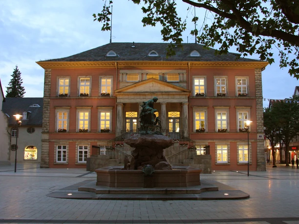 Detmold Rathaus mit Donop Brunnen Beleuchtetes Rathaus Detmold mit klassizistischer Fassade hinter dem Donop-Brunnen am Abend.