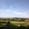 Schöne Aussicht Weitläufige Landschaft mit Feldern und Hügeln, im Vordergrund ein Dorf mit traditionellen Häusern.