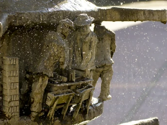 Marktplatz_Brunnen_Detail_01©Tourist-Information Lage.jpg Wasser spritzt aus einem kunstvoll gestalteten Brunnen mit detailreichen Figuren in enger Interaktion.