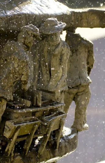 Marktplatz_Brunnen_Detail_01©Tourist-Information Lage.jpg Wasser spritzt aus einem kunstvoll gestalteten Brunnen mit detailreichen Figuren in enger Interaktion.