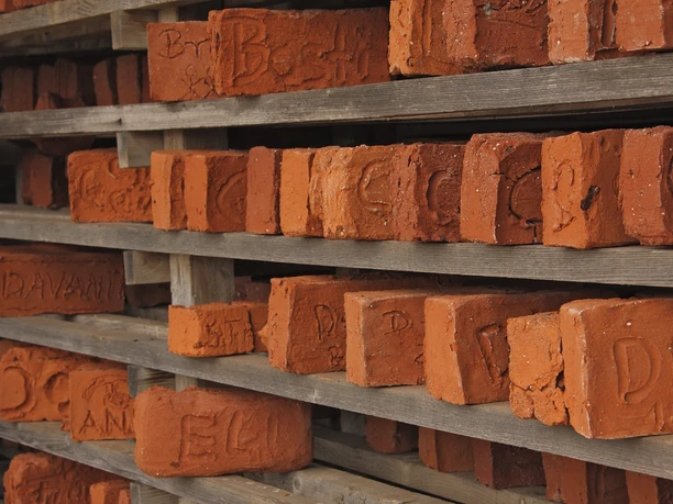 Ziegeleimuseum Besucherziegel©Foto LWL.jpg Ziegel in Regalen gestapelt, mit handgeschriebenen Inschriften für das Ziegeleimuseum LWL.