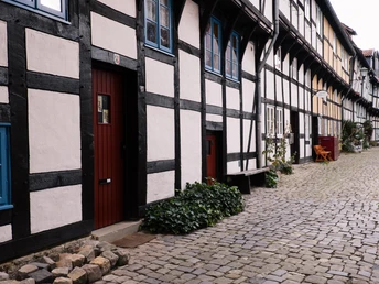 Fachwerkhäuser säumen eine gepflasterte Gasse in Detmolds historischer Altstadt, Pflanzen schmücken die Fassade.