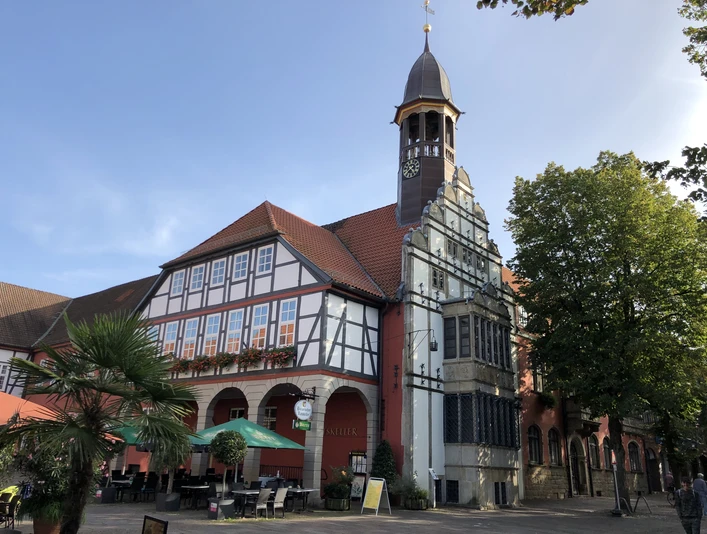 Rathaus Nienburg Rathaus Nienburg mit Fachwerk und Uhrturm, umgeben von Bäumen und einem Café im Vordergrund.Nienburg town hall with half-timbered building and clock tower, surrounded by trees and a café in the foreground.Nienburgs rådhus med bindingsværksbygning og klokketårn, omgivet af træer og en café i forgrunden.Stadhuis van Nienburg met vakwerkgebouw en klokkentoren, omringd door bomen en een café op de voorgrond.