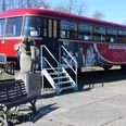 historischer Schienenbus Ein roter, historischer Zug steht auf einem Gleis. Neben dem Zug befindet sich eine steinerne Skulptur einer Frau.
