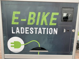 E-Bike-Ladestation Ladestation für E-Bikes mit grünem Schriftzug und Steckersymbol, geeignet für zwei Ladeboxen.