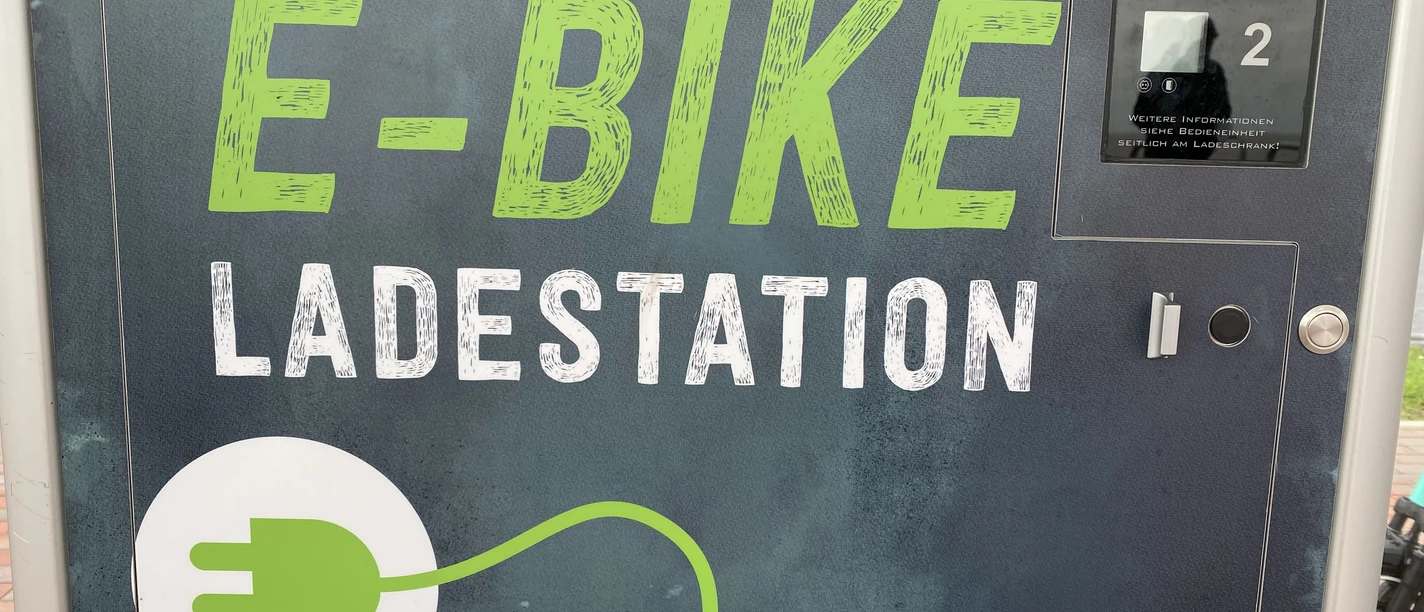E-Bike-Ladestation Ladestation für E-Bikes mit grünem Schriftzug und Steckersymbol, geeignet für zwei Ladeboxen.