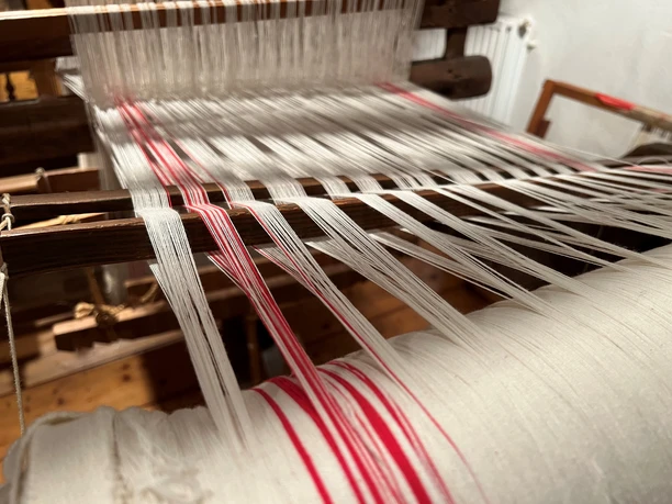 Webstuhl Historischer Webstuhl zeigt komplexe, kontrastreiche Verknüpfung von weißen und roten Fäden.