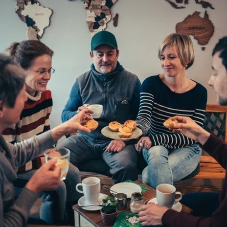 Eine Gruppe Menschen sitzt mit Kaffee zusammen und probiert süße Pasteis im Rahmen der kulinarischen Stadtführung von allerleipzig.