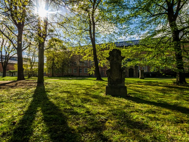 View over the meadow and the planting of the Johannisfriedhof cemetery and the brick buildings in the background