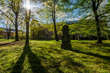 Alter Johannisfriedhof - Kultureinrichtungen in Leipzig Blick über die Wiese und die Bepflanzung des Johannisfriedhofs sowie die Backsteingebäude im Hintergrund